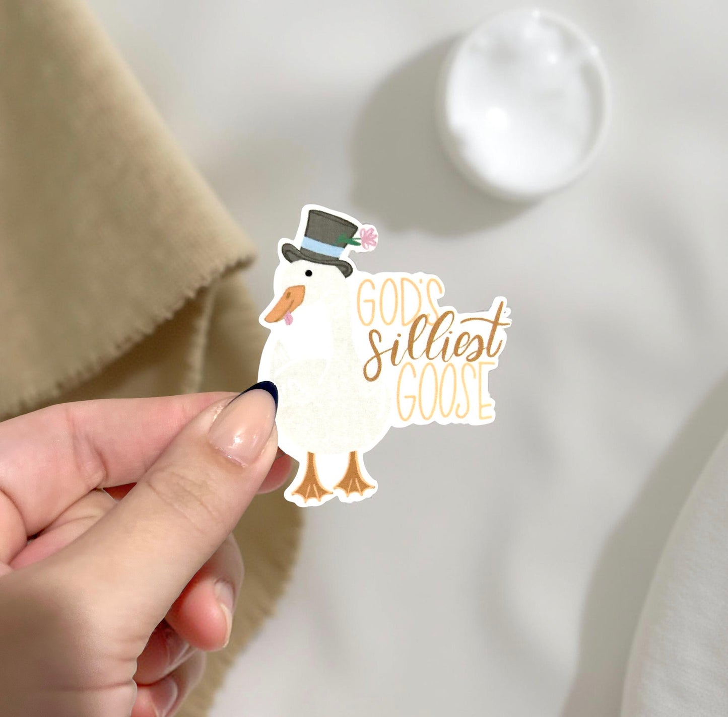 hand holding sticker that reads God's Silliest Goose
