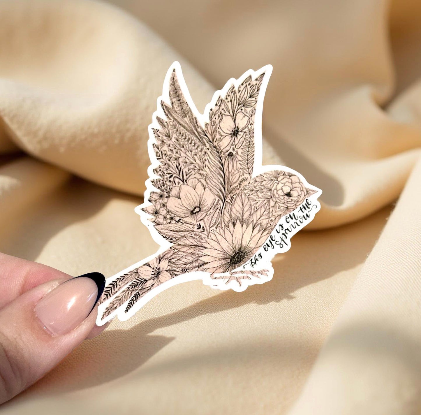 Decorative sticker with intricate design held by a hand on beige fabric