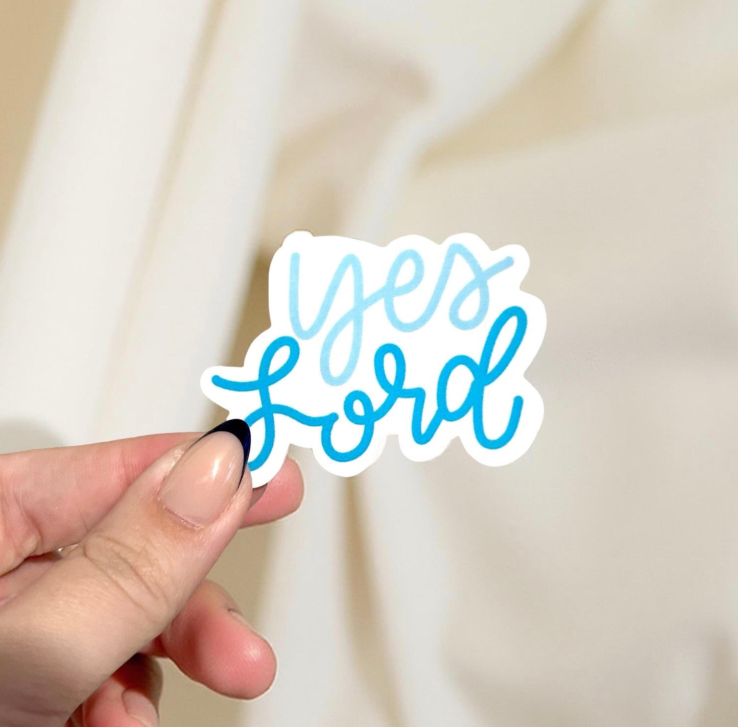 Hand holding a sticker with 'Yes Lord' text against a light background