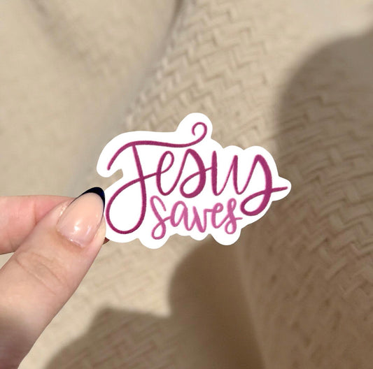 Hand holding a 'Jesus Saves' sticker against a beige background