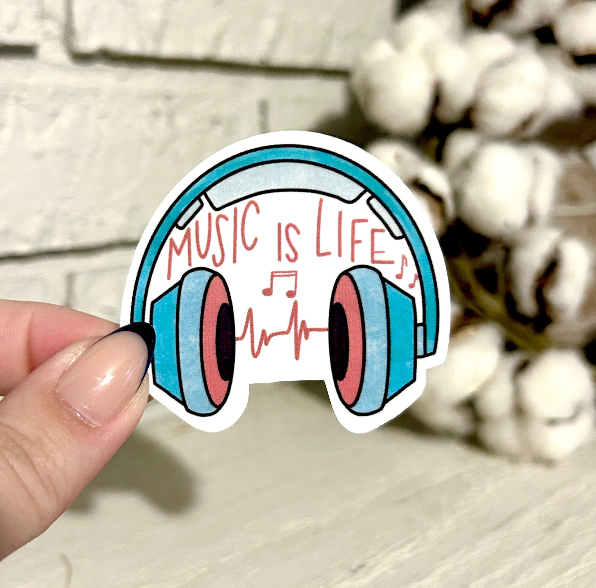 Sticker of  Headphones that say music is life held by hand