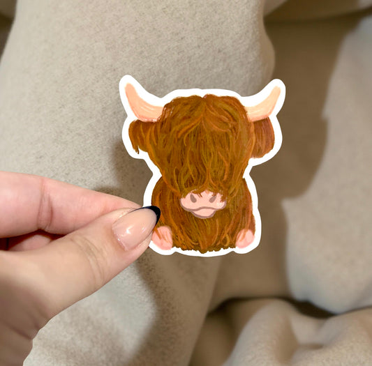 sticker of highland cow being held in front of fabric