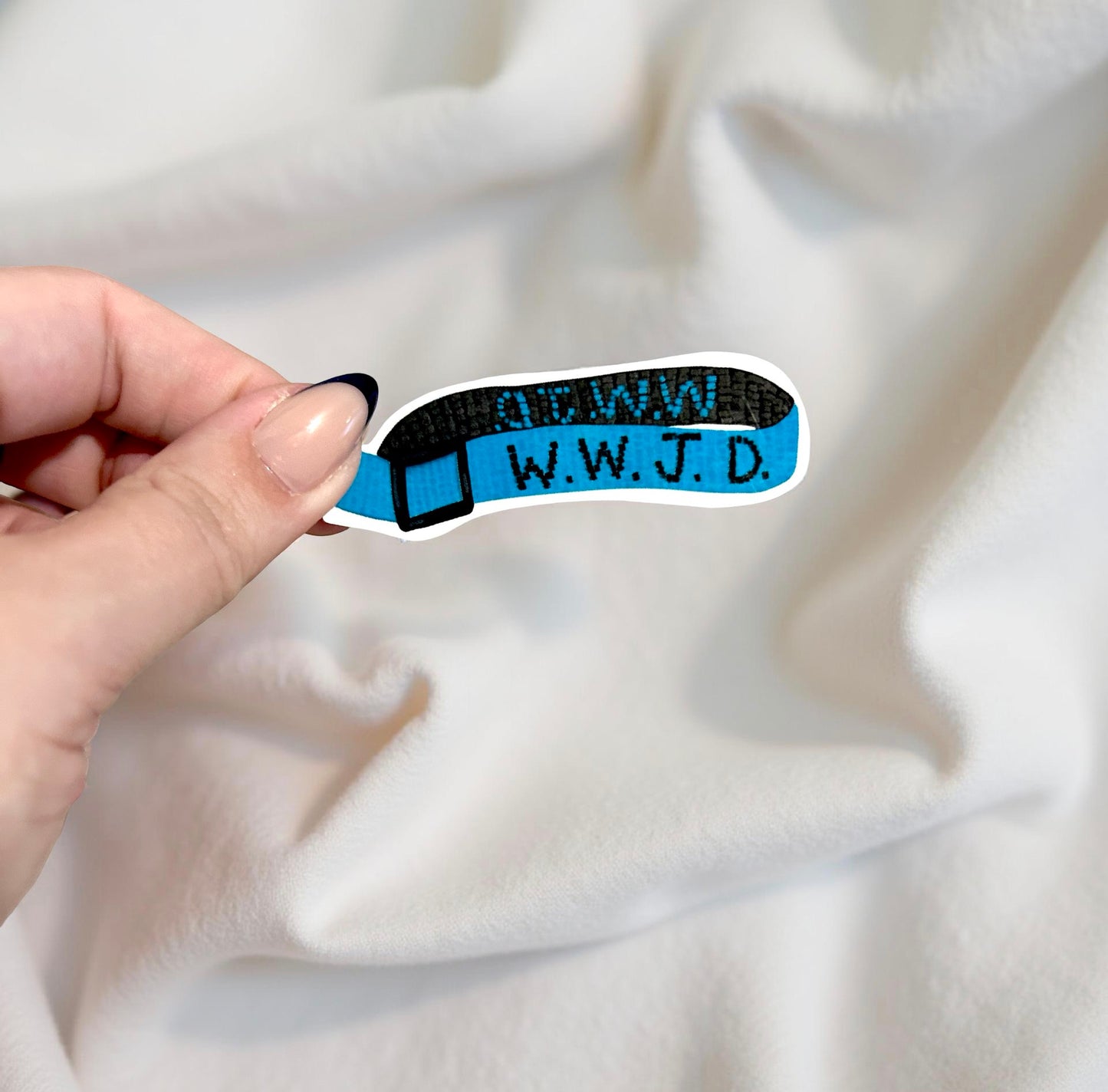 Hand holding sticker of a wwjd bracelet on beige background 