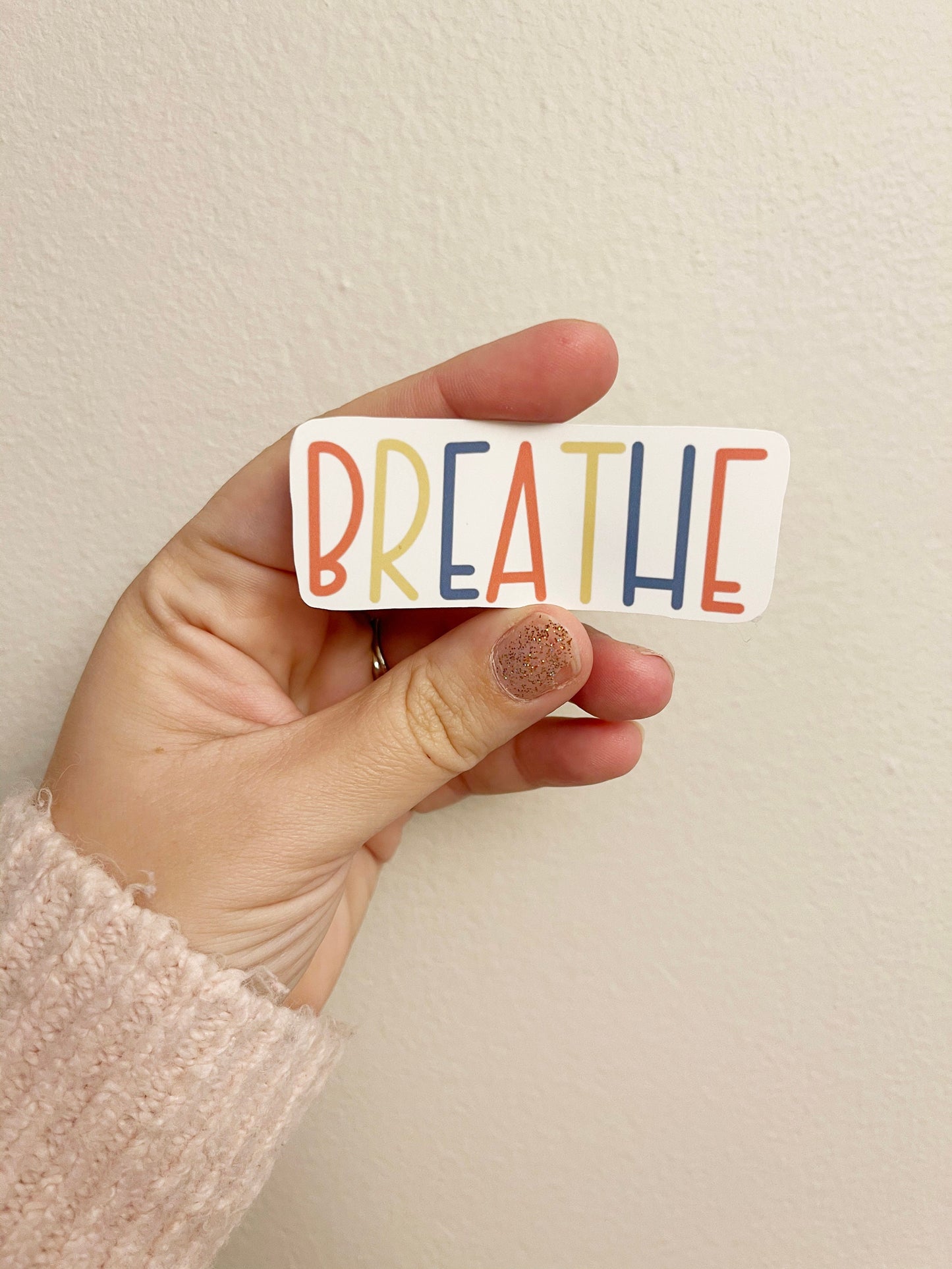 hand holding a sticker that reads breathe